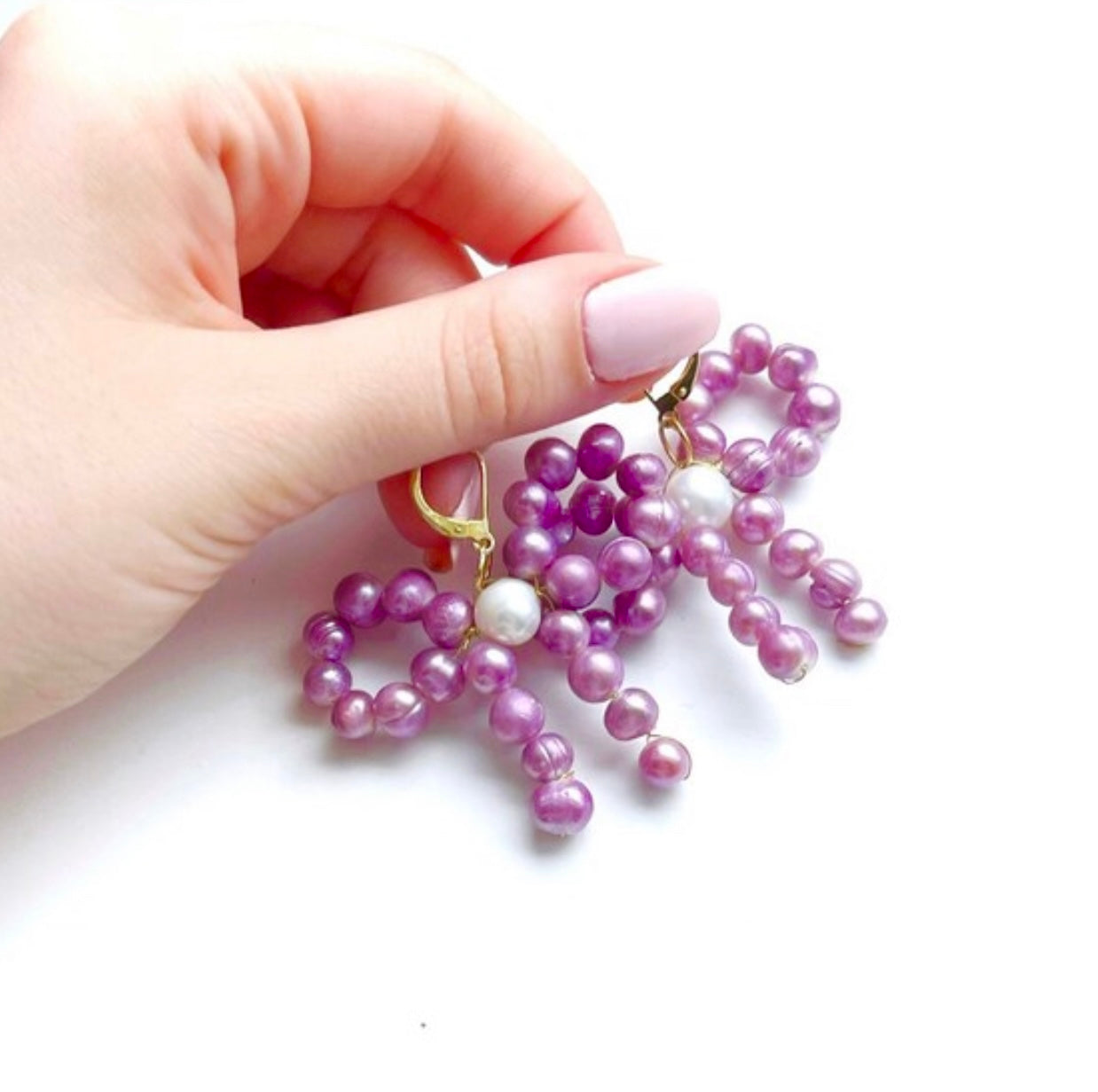 Bow dangle and drop pearl statement earrings with purple and white freshwater pearls, unique modern pearl jewelry trends 2022