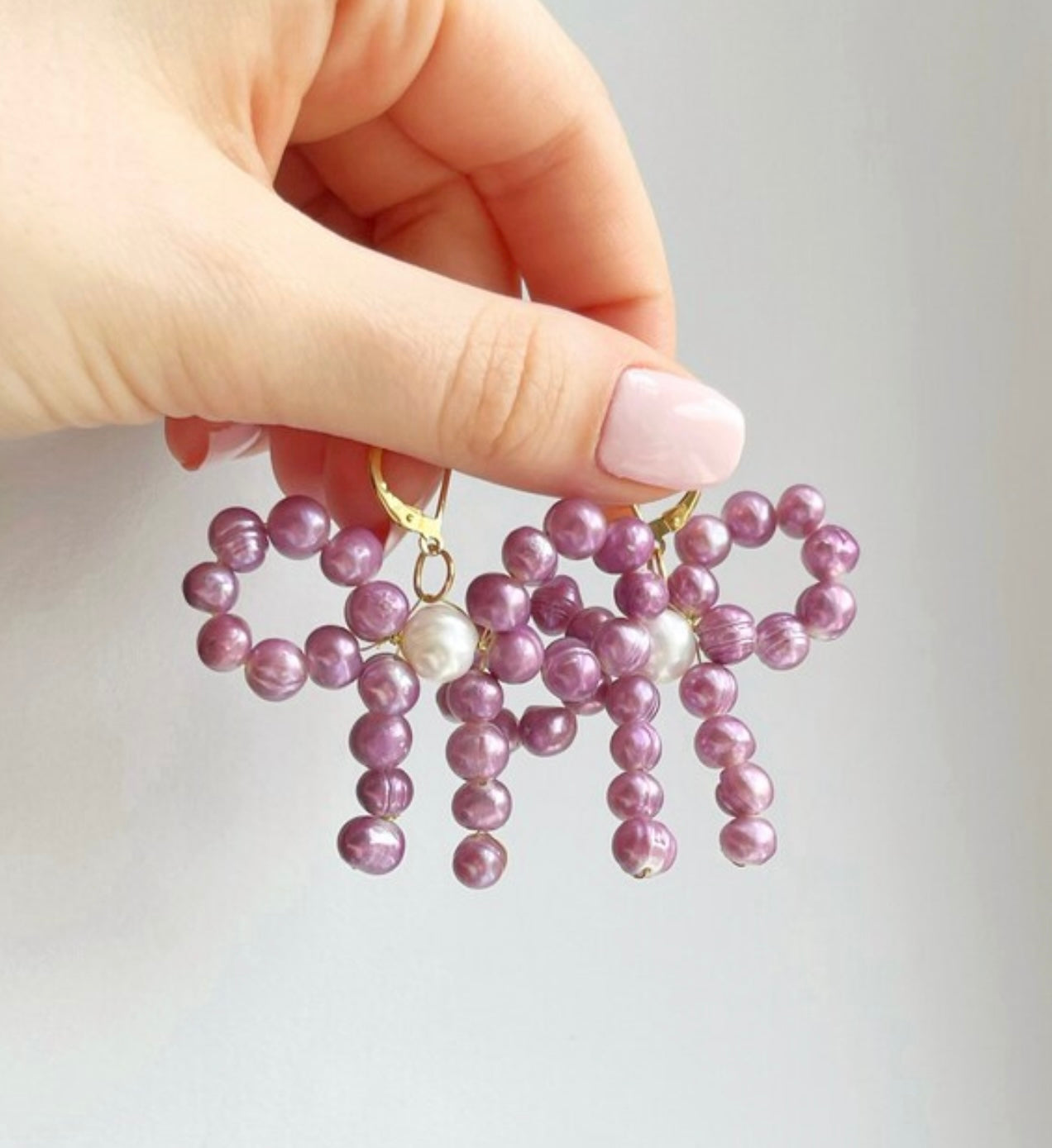 Bow dangle and drop pearl statement earrings with purple and white freshwater pearls, unique modern pearl jewelry trends 2022